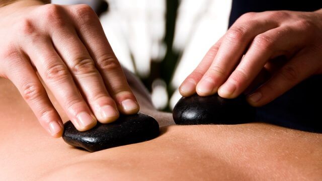 Terpeuta con piedras calientes para masaje